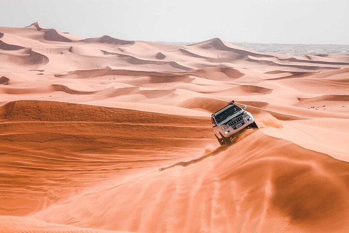 Experience the breathtaking beauty of Dubai’s golden sand dunes as you embark on an unforgettable adventure filled with dune bashing sandboarding and camel riding amid serene sunrise views.